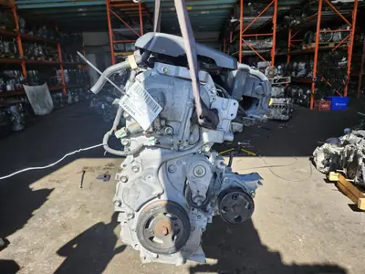 Used Nissan Sentra 1.8L MRA8 engine hanging from a chain hoist